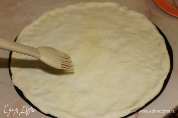 Отделите кусочек теста и сформируйте тонкую основу для пиццы с бортиком по краю. Смажьте основу оливковым маслом.