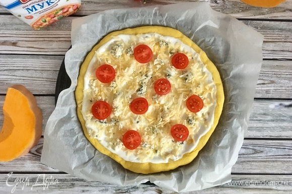 Сверху посыпать сыром и разложить помидоры. Выпекать при 200°C 15–20 минут. Готовую пиццу по желанию можно украсить свежей зеленью.