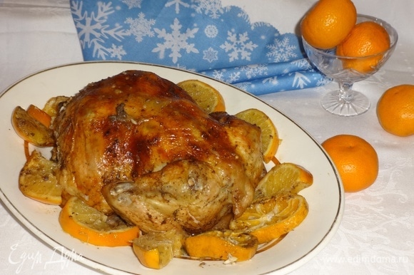 Достать из духовки форму с готовой курицей. Пока курица лежит в форме, аккуратно достать вилкой дольки цитрусовых. Выложить курицу на блюдо. Вокруг разложить мандарины и апельсины. Подать курицу на новогодний стол, дополнив гарниром по желанию. Всем приятного аппетита! С Новым годом!