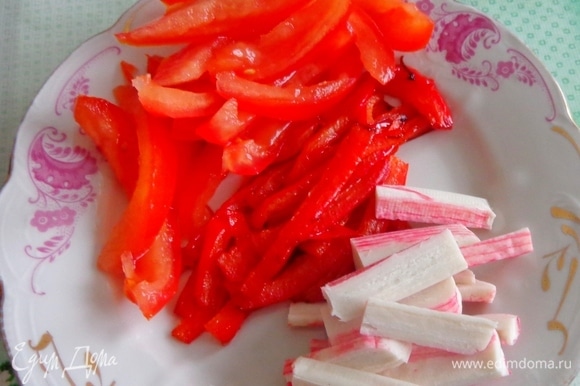 Красный болгарский перец нарезать тонкими пластинками и слегка обжарить. Помидор освободить от семян и лишней жидкости и нарезать пластинками. Такими же пластинками нарезать крабовые палочки.