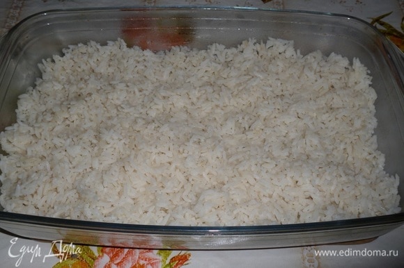 В форму для запекания выкладываем отварной рис, равномерно распределяем.