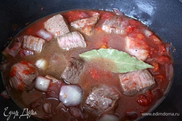 Поместить мясо в жаровню, добавить консервированные в собственном соку томаты, бульон. Мясо должно быть не до конца покрыто жидкостью. Кусочки мяса должны быть видны на поверхности жидкости. Добавить лавровый лист.