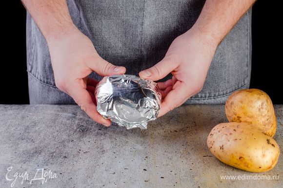 С помощью специальной щеточки хорошо промойте картофель. Не чистите. Оберните каждую картофелину в фольгу и запеките в духовке при 180°С в течение 50 минут до готовности. Ориентируйтесь по своей духовке.