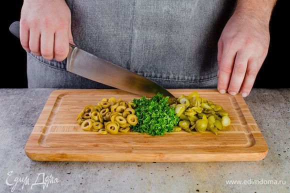 Нарежьте мелко огурцы, оливки, петрушку и укроп.