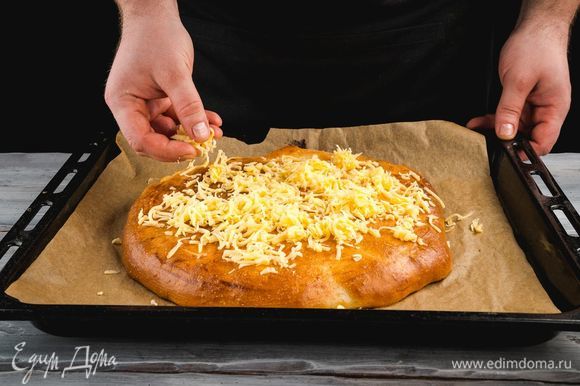 Достаньте пирог, посыпьте его обильно тертым сыром и уберите в духовку еще на 5 минут.