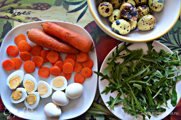 Отварите и почистите перепелиные яйца. Каждое разрежьте пополам. Морковь отварите до готовности, почистите и нарежьте кружочками. Руколу помойте и просушите.