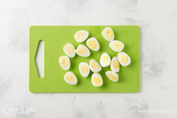 Отварить перепелиные яйца и разрезать пополам.