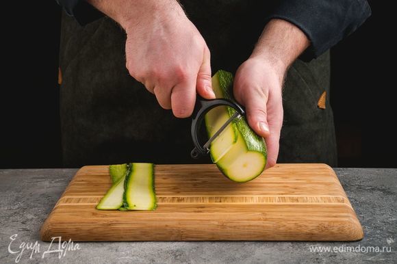 Цукини с помощью овощечистки нарежьте тонкими слайсами.