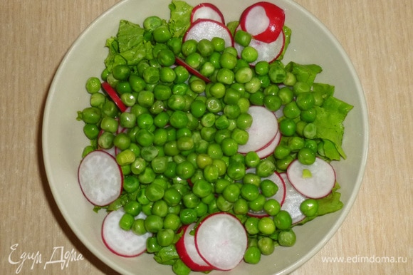 В салатник сложить нарезаные салатные листья, тонко нарезанный редис, добавить горошек.