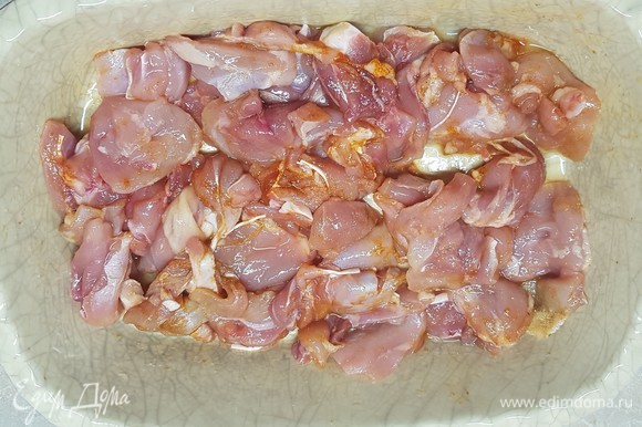 Мясо срезать с куриных бедер и нарезать небольшими кусочками. Посолить, добавить любимую приправу. Сложить в форму для запекания.
