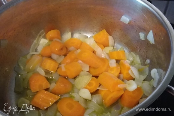На разогретом оливковом масле пассеровать нарезанные лук и чеснок до прозрачности, добавить нарезанную морковь и обжарить в течение нескольких минут.