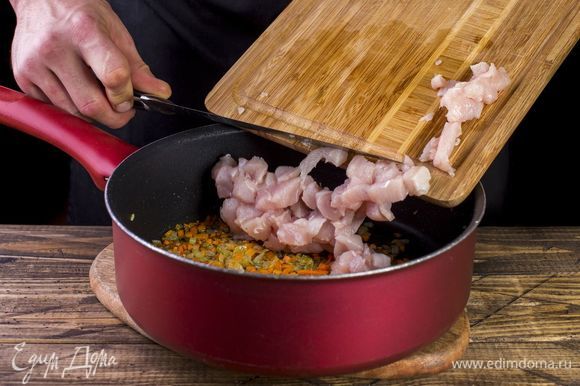 В глубокой сковороде обжарьте до мягкости лук и морковь. Добавьте к ним куриное филе и тушите пять минут.