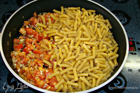 К обжаренным овощам всыпать пачку макарон (450–500 г), посолить и поперчить по вкусу.