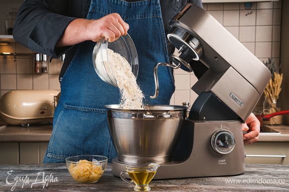 В чашу кухонной машины добавьте лук и 1 ст. л. оливкового масла. С помощью насадки для смешивания хорошо перемешайте ингредиенты. Далее используйте насадку крюк, чтобы замешать тесто. Постепенно добавляйте муку, чтобы получилось мягкое, слегка прилипающее к рукам тесто и замесите тесто с помощью насадки крюк. Поставьте тесто на расстойку в теплое место на 1 час.