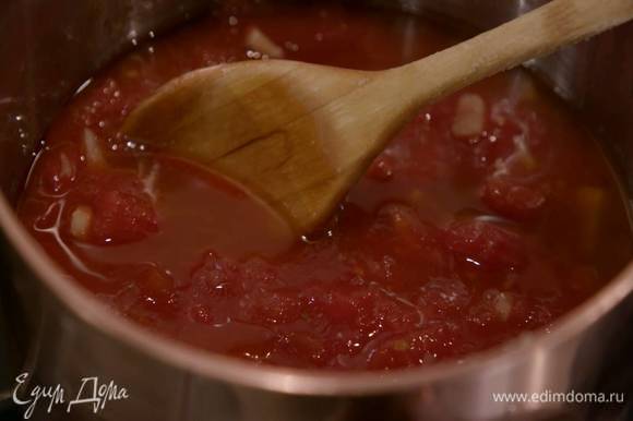 Приготовить томатный соус: четыре зубчика чеснока почистить, мелко порубить и обжарить в тяжелой кастрюле на оливковом масле, затем добавить консервированные помидоры, посолить и, помешивая, уварить, так чтобы соус загустел.