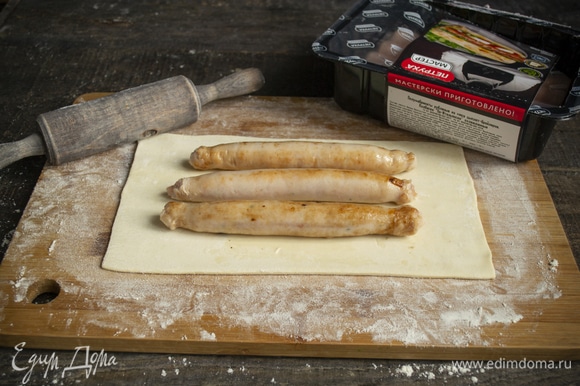 На неразрезанный лист теста кладем остывшие колбаски, нужно по 3 штуки на 1 пирожок.