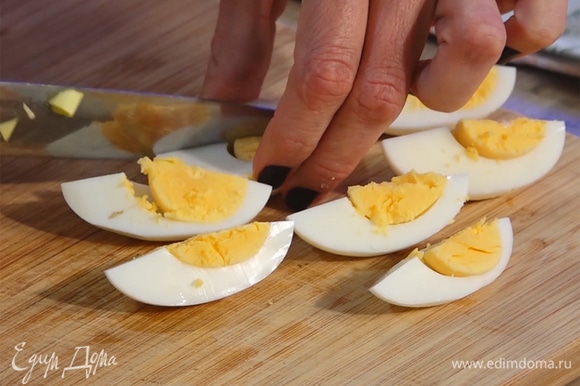 Яйца разделить на дольки. Нарезать укроп и петрушку.