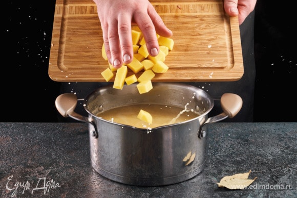 Картофель почистите и нарежьте небольшими кусочками. Опустите в бульон, где варится горох.