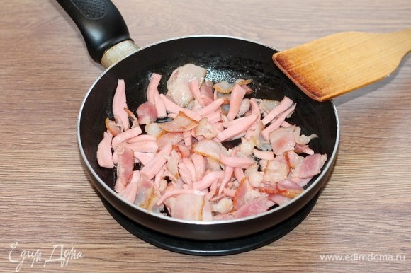 Выложить бекон в сухую сковороду и обжарить его на слабом огне до выделения смальца. Затем добавить кусочки колбасы и на среднем огне, помешивая довести мясную смесь до румяности.