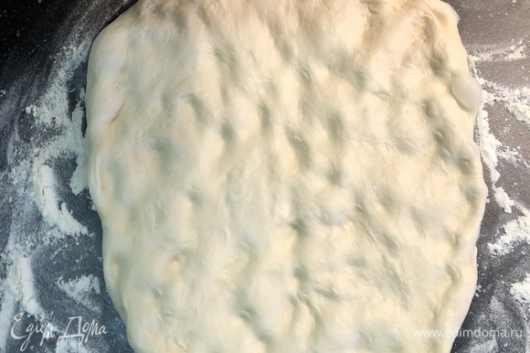 Разогреть духовку до максимальной температуры 270–300°C. За 10 минут до выпекания достать тесто из холодильника. Тесто растянуть руками, надавливая пальцами.