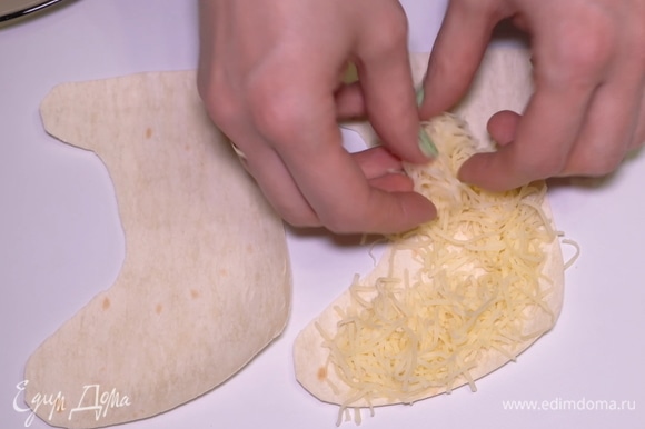 Берем нарезанный лаваш и начинаем оформлять закуску. Кладем один носочек снизу, посыпаем обильно тертым сыром.