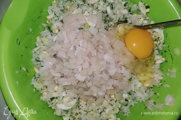 В чашку выкладываем нарезанные кальмары, сырое яйцо, солим, перчим и перемешиваем.