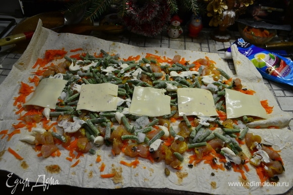 Слоями выкладываю отварную морковь, натертую на терке, кусочки куриной грудки, нарезанной на кубики, фасоль зеленую, майонез и сверху в ряд пластинки сыра. Сворачиваем в рулет.