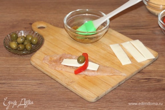Положите на полоску кусочек сыра и оливку.