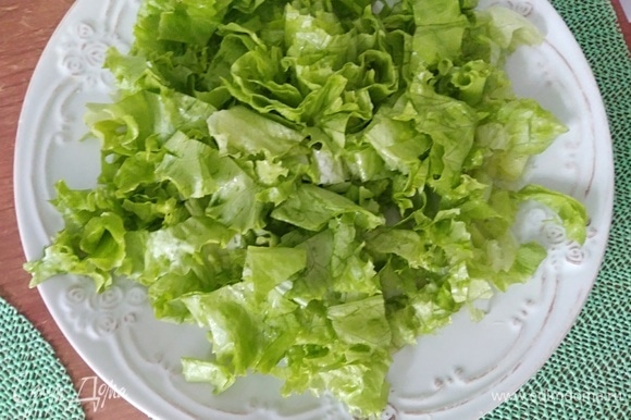 Листовой салат промыть холодной водой, обсушить и порвать руками на большую тарелку.