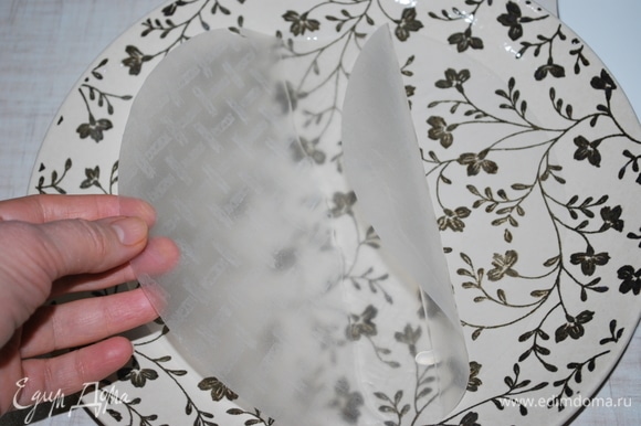 В тарелку налейте теплую воду, возьмите лист рисовой бумаги и окуните его на 8–10 секунд, чтобы он не сильно размяк.