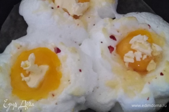 На каждое яйцо положить кусочек сливочного масла. Поставить обратно в духовку на 10 минут.