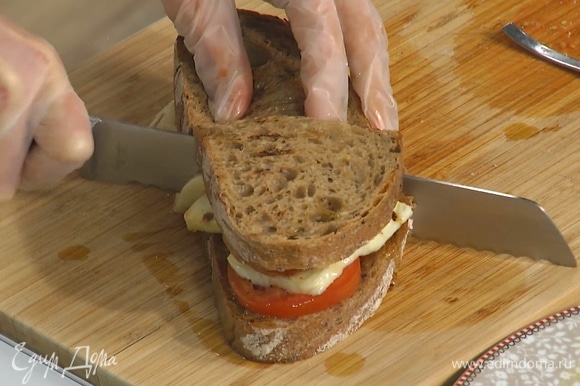 Второй кусок хлеба смазать пастой харисса и полить оливковым маслом, затем накрыть им бутерброд, сильно прижать и разрезать пополам.