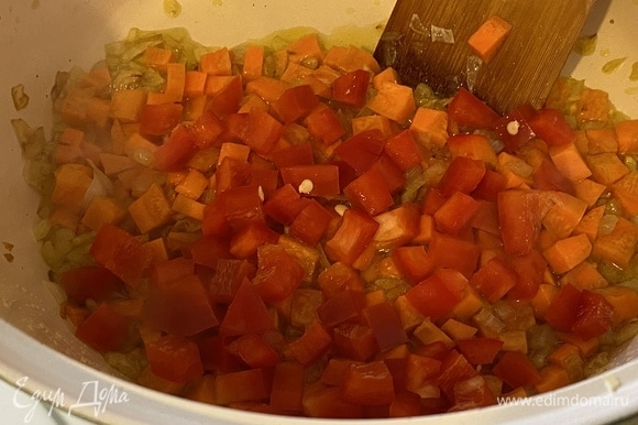 Через 3 минуты добавить болгарский перец, тоже нарезанный кубиком. Продолжать обжаривать овощи, постоянно помешивая.