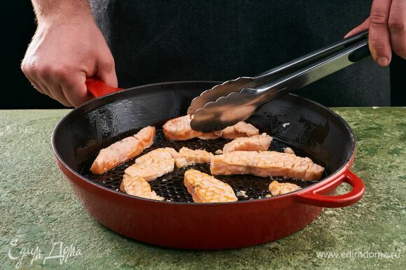 Лосося нарежьте полосками. Разогрейте сковороду с оливковым маслом и выложите рыбу.