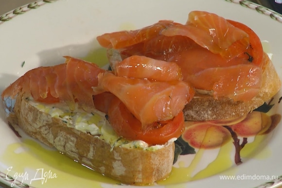 Намазать подсушенный хлеб заправленным сливочным сыром, сверху разложить кусочки помидора и ломтики лосося, полить оставшимся оливковым маслом.