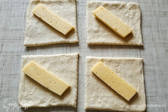 Слоеное дрожжевое тесто разрезать на 4 части. Положить кусочек сыра.
