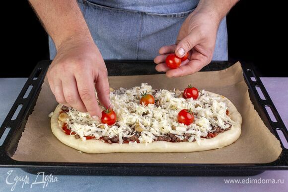 Выложите помидоры черри. Загните края пиццы по бокам и выпекайте в разогретой до 220 °С духовке 10–12 минут.