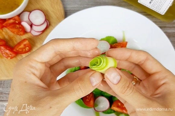 В тарелку выкладываем зелень, редис, томаты. Из слайсов кабачка крутим рулетики.
