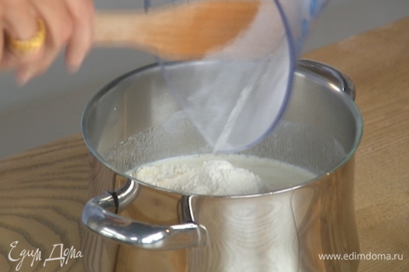 Муку перемешать с разрыхлителем, всыпать в горячее молоко и вымешивать, пока тесто не остынет настолько, что его можно будет касаться рукой.