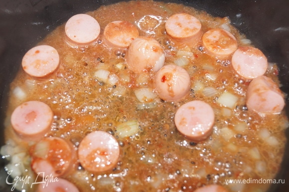 Обжарьте нарезанные сосиски с луком и чесночным кетчупом 5 минут с растительным маслом в мультиварке на функции «жарка».