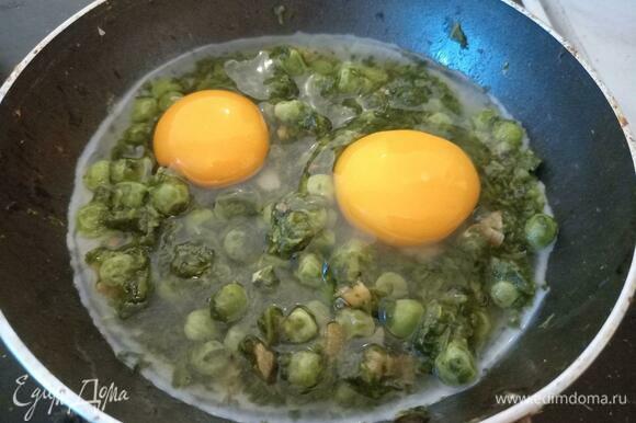 Сразу же аккуратно разбить два яйца поверх смеси, стараясь не повредить желток. Закрыть крышкой на две минуты, чтобы белок лучше схватился, но желток при этом оставался сырым.