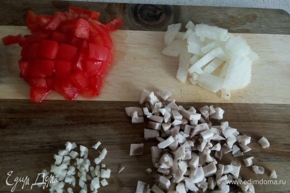 Пока баклажаны запекаются, готовим начинку. Нарезаем кубиками лук, шампиньон, помидор и чеснок.