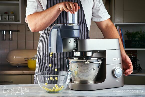 Овощи для супа очистите. Установите на кухонную машину насадку-овощерезку и нарежьте кубиками картофель и очищенный помидор.