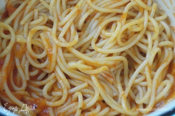 Пока курочка запекается, отварите спагетти в большом количестве подсоленной воды. Слить воду и переложить спагетти к оставшемуся томатному соусу. Перемешать.
