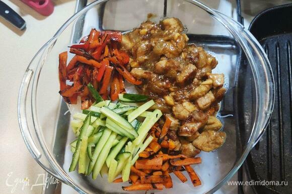 В миску с фунчозой добавить содержимое двух сковородок (мясо с луком и перец с морковью), а также нарезанные соломкой огурцы и зелень.