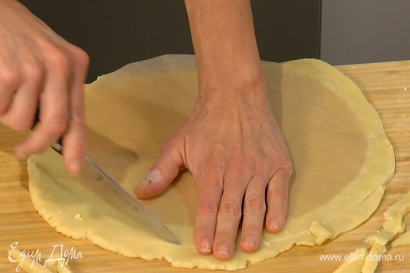 Вымесить тесто руками и раскатать в тонкий корж, края обрезать так, чтобы корж был на полтора сантиметра больше формы.