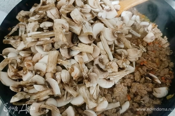 Нарезать грибы. Со сковороды убрать чеснок Добавить шампиньоны в сковороду к фаршу. Обжаривать в течение 3–4 минут.
