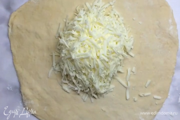 Натираем сыр на крупной терке. Раскатываем тесто не слишком тонко, чтобы получился круг. Выкладываем часть начинки в середину.