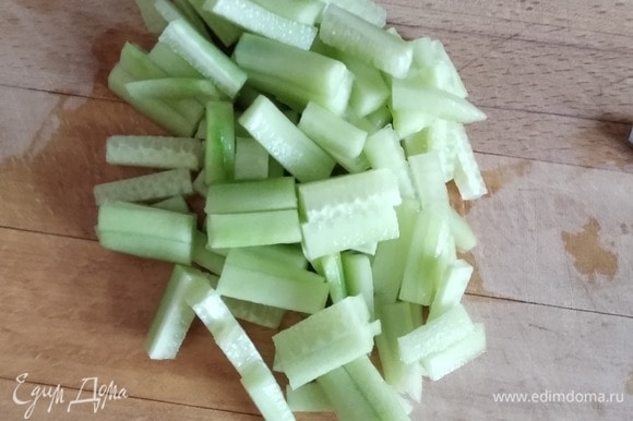 Огурец (у меня один длинноплодный, можно взять 3–4 короткоплодных) нарезать тонкими брусочками. Добавить к капусте и моркови.