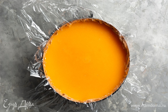 Достать форму с чизкейком из морозилки (или холодильника), снять пленку, поверх залить мандариновым пюре. Накрыть пленкой и убрать в холодильник на 6–8 часов, до полного застывания (лучше — на ночь).